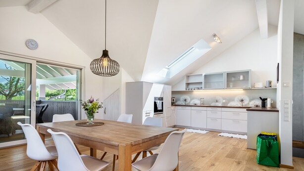 Una cocina moderna con armarios blancos, una mesa de comedor de madera y sillas blancas.