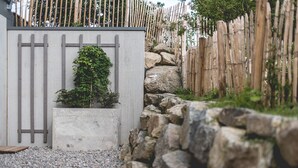 A concrete planter with a small tree, a wooden fence, and a stone wall.