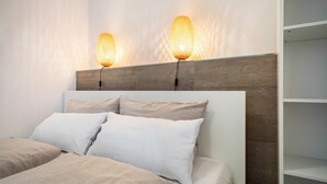 A modern bedroom with a wooden headboard, two bedside lamps, and a white bed with beige bedding.