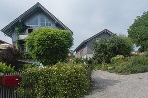 A residential building with a sloped roof, a balcony, and a gravel driveway. - Apartment '2' with Shared Garden and Wi-Fi (Lindau am Bodensee)