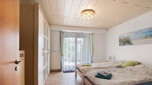 Un dormitorio con cama, una ventana con cortinas, un cuadro en la pared y una lámpara en el techo.