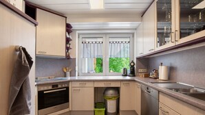 Una cocina moderna con horno empotrado, lavavajillas y una ventana con cortinas.
