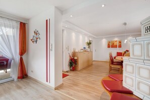 Une chambre d’hôtel moderne avec un plancher en bois, un coin repas comprenant une table et des chaises, et une armoire blanche avec des tiroirs.