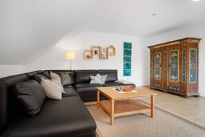 Un salon moderne avec un canapé en cuir noir, une table basse en bois et un meuble agrémenté de panneaux décoratifs.
