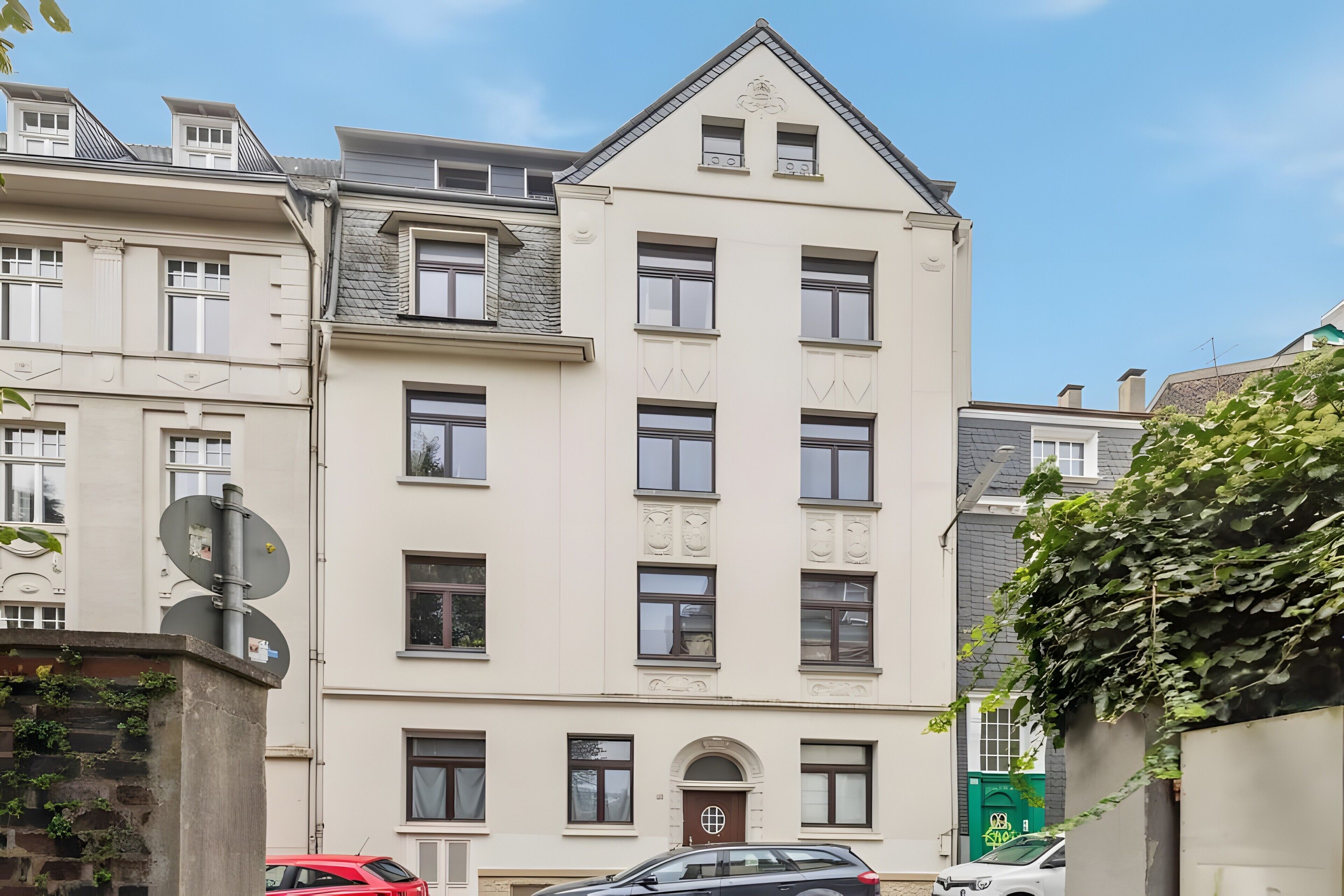 Ein mehrgeschossiges Gebäude mit einer symmetrischen Fassade, zahlreichen Fenstern und einem zentralen Eingang.