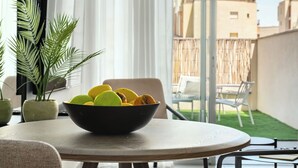 A round table with a black bowl containing fruit, a potted plant, and a view of a balcony with chairs and a bamboo fence. - Red Canyon Peaceful Stay by Sea N' Rent (Eilat)