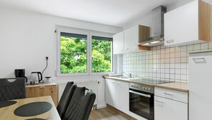 A modern kitchen with white cabinets, a built-in oven, and a window with a view of greenery.