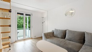 A modern living room with a grey sofa, a small white table, and a wooden ladder.