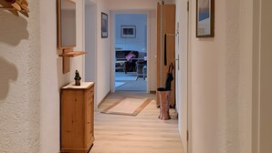 Ein Flur mit einem Holzkasten, einem Spiegel und einer Tür zu einem anderen Raum.