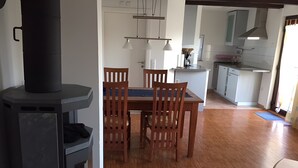 A dining area with a table and chairs, a black stove, and a kitchen in the background.