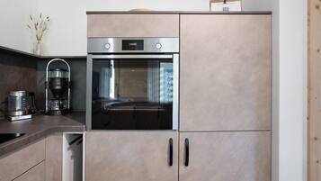 A modern kitchen with a built-in oven, a coffee maker, and a dishwasher.