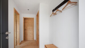 A hallway with wooden flooring, a bench, a coat rack, and a door.