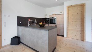A modern kitchen with a central island, built-in appliances, and a wooden door.