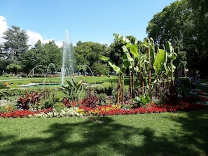 Un jardin agrémenté d’une fontaine, de bananiers et d’une grande variété de fleurs aux couleurs vives.