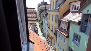 Eine enge Straße mit Gebäuden, die rote Ziegeldächer und Balkone haben.