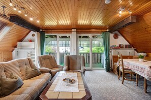 Une pièce chaleureuse avec un plafond en bois, un canapé, une table et une vue sur un jardin.