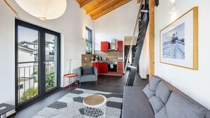 A modern living room with a sofa, a coffee table, and a kitchen in the background. - Apartment 'Sonnenwind Am Hainer See' with Lake View and Wi-Fi (Neukieritzsch)