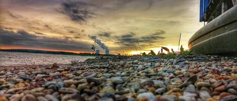 A pebbled beach with a sunset in the background.