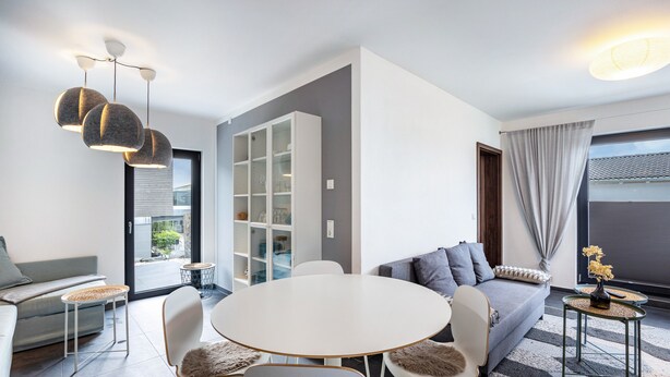 Een moderne woonkamer met een ronde tafel, banken en een ingebouwde boekenkast.