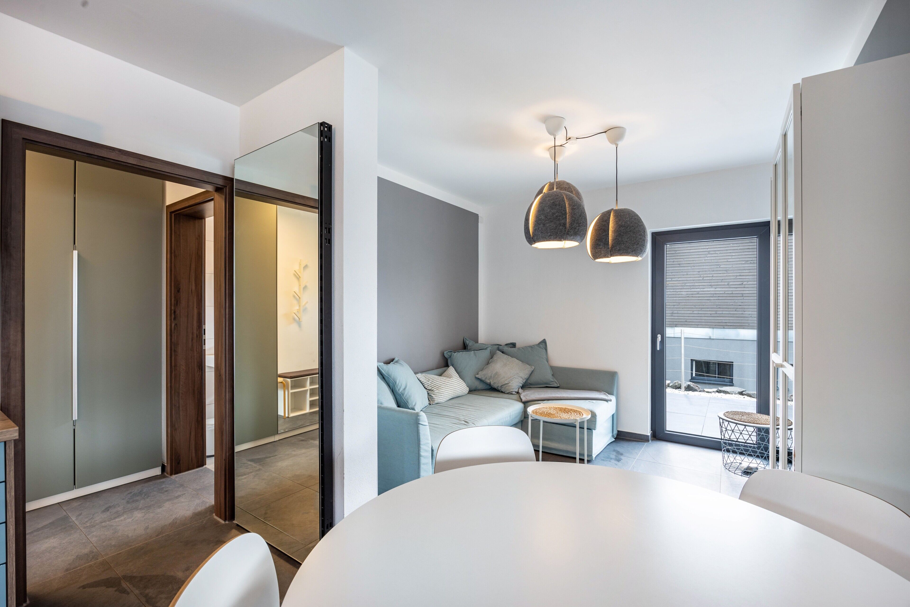 A modern interior with a sofa, dining table, and pendant lights.