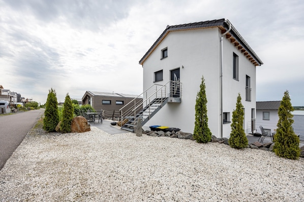 A modern building with a staircase, outdoor seating, and a gravel driveway.