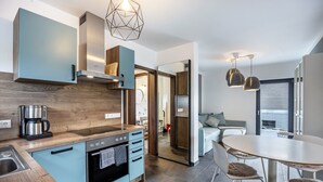 Een moderne keuken met een koffiezetapparaat, oven, en een eethoek met een ronde tafel en stoelen.