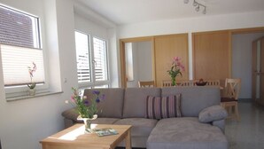 Una sala de estar con sofá, una mesa de centro y un comedor con sillas.