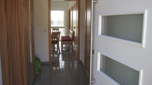 Un pasillo con puerta de madera, una silla y una mesa.