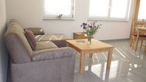 Un salon avec un canapé, une table en bois et un vase rempli de fleurs.