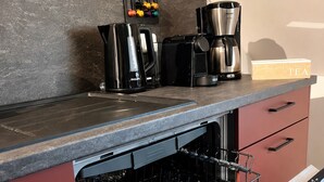 Uma cozinha com uma cafeteira, uma chaleira e uma caixa de chá no balcão.