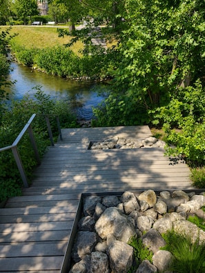 A wooden deck with a railing, leading to a rocky area with greenery. - Comfort-Apartment-93m²-Central-Near Stadtpark (Pfaffenhofen an der Ilm)