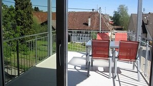 A balcony with a table and chairs, a metal railing, and a view of houses and trees. - Apartment 'Golden Delicious' with Shared Terrace, Shared Garden and Wi-Fi (Salem)