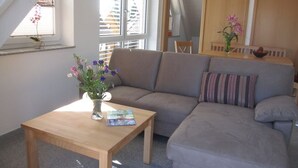 A living room with a sofa, a wooden coffee table, a vase with flowers, and a window with blinds. - Apartment 'Golden Delicious' with Shared Terrace, Shared Garden and Wi-Fi (Salem)