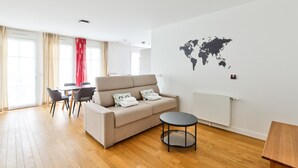 A modern living room with a sofa, a round table, and a dining area with chairs. - Puteaux - La défense - 2 chambres (Puteaux)
