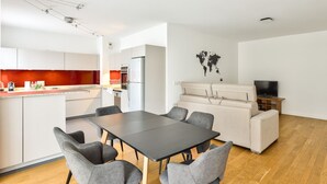 A modern kitchen with white cabinets, a red backsplash, and a dining area with a black table and grey chairs. - Puteaux - La défense - 2 chambres (Puteaux)