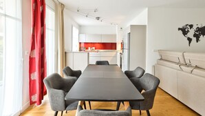 A modern living room with a dining area, a kitchen in the background, and a world map on the wall. - Puteaux - La défense - 2 chambres (Puteaux)