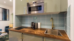 A modern kitchen with a built-in oven, a sink, and a coffee maker. - 3. cosy 1BR - Père Lachaise - Nation (Paris)