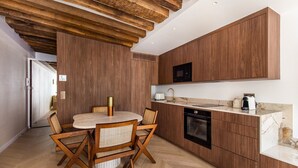 A modern kitchen with wooden cabinets, a round dining table, and a herringbone floor pattern. - Luxury - 1BR - Louvre/Saint Honoré/palais Royal-AC (Paris)