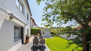 Una casa con un patio, un cobertizo pequeño y un césped bien cuidado.