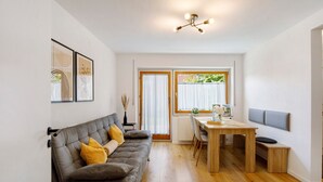 Una sala moderna con sofá, mesa de comedor y zona de cocina.