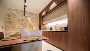 A modern kitchen with a stone wall, wooden cabinets, and a central island with woven placemats.