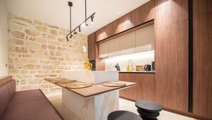 A modern kitchen with a stone wall, wooden cabinets, and a central island with woven placemats.