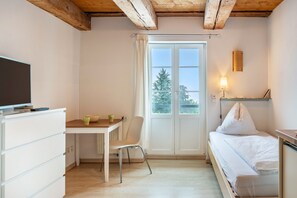 A room with a bed, a desk with a chair, a television, and a window with curtains. - Apartment 'Halden' with Wi-Fi (Heiligenberg)