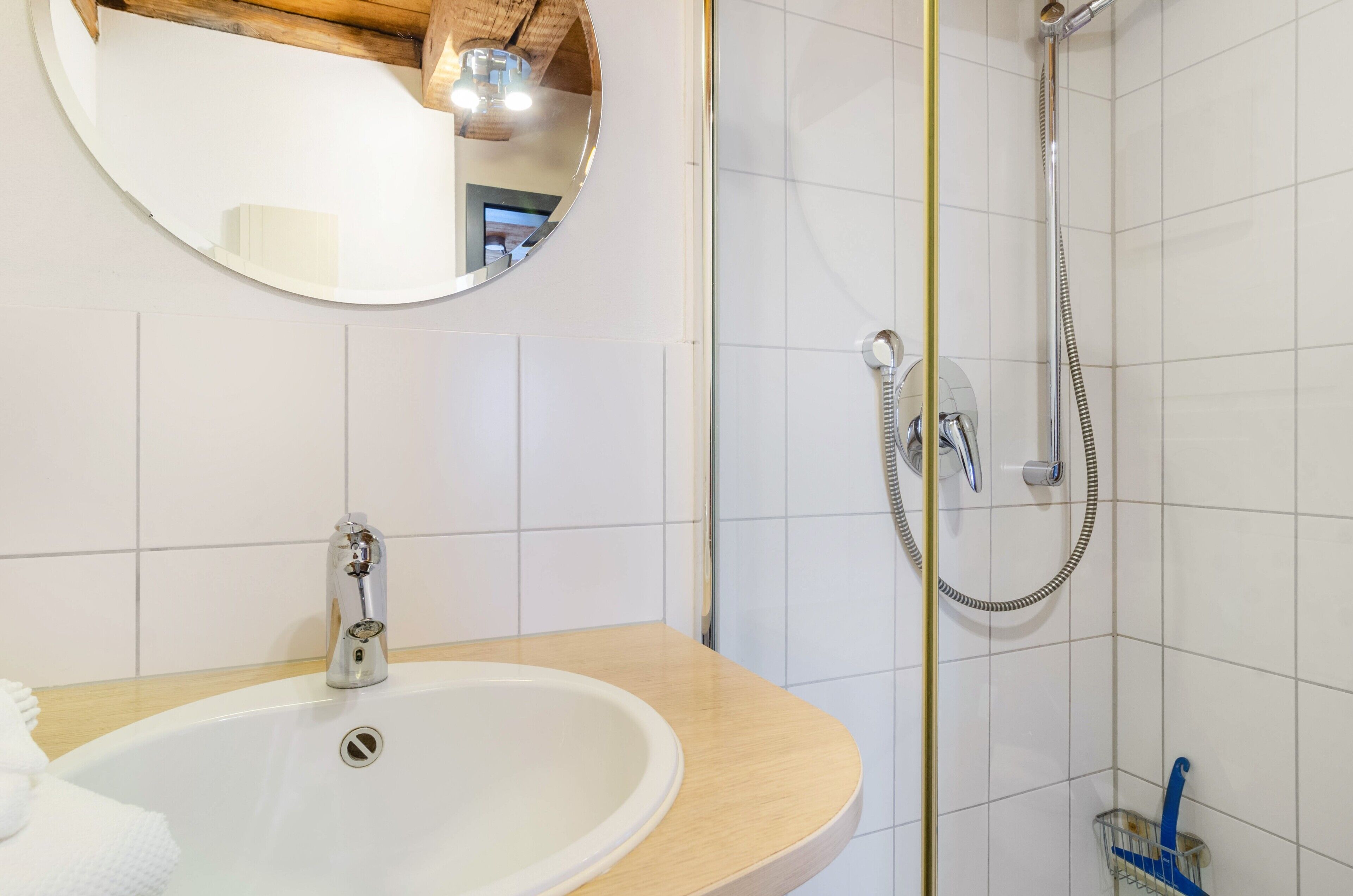 Une salle de bain avec un lavabo, un miroir, une douche et des murs carrelés.