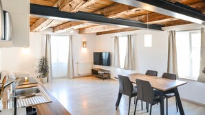 A modern kitchen with a wooden ceiling, a dining area with a table and chairs, and a television mounted on the wall. - Apartment 'Steigen' with Wi-Fi (Heiligenberg)