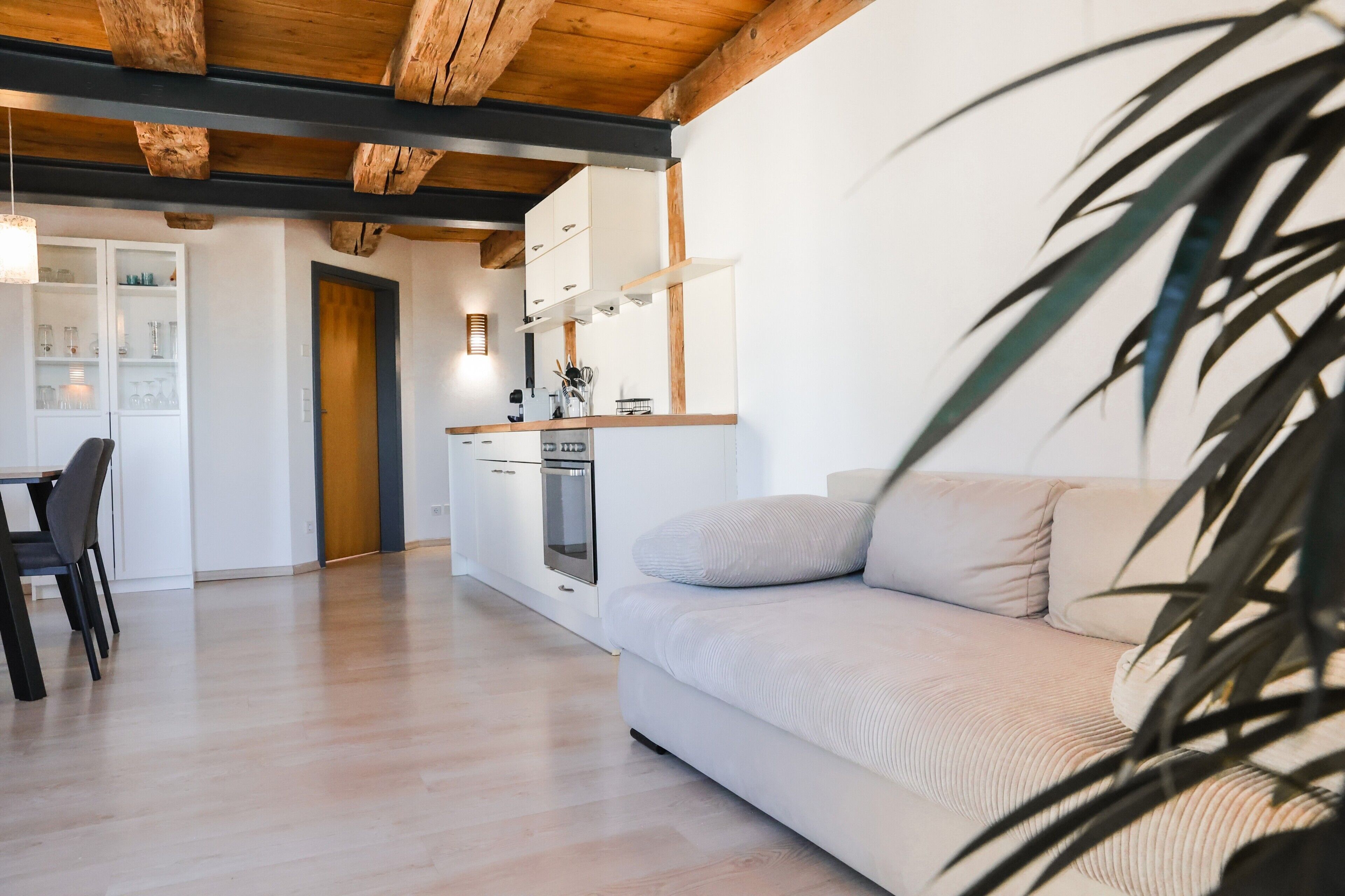 A modern kitchen with white cabinets, a wooden ceiling, and a dining area with a table and chairs.