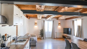 A modern kitchen with a wooden ceiling, a dining area with a table and chairs, a sofa, and a TV. - Apartment 'Steigen' with Wi-Fi (Heiligenberg)