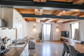 A modern kitchen with a wooden ceiling, a dining area with a table and chairs, a sofa, and a TV. - Apartment 'Steigen' with Wi-Fi (Heiligenberg)