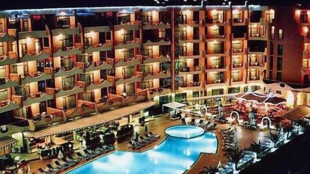 Ein mehrstöckiges Hotel mit Balkonen, einem Schwimmbad und Außenbereich-Sitzgelegenheiten.