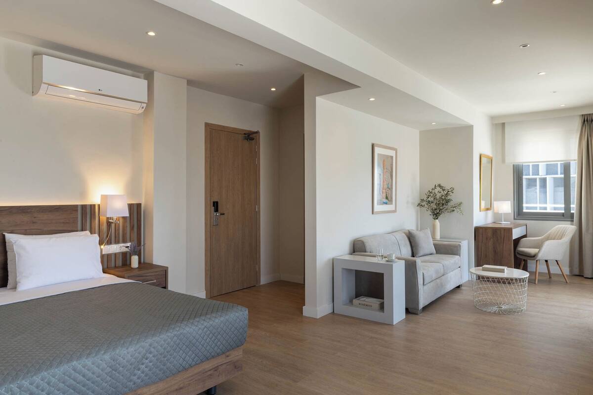 Ein modernes Hotelzimmer mit Bett, einer Couch, einem kleinen Tisch und einem Schreibtisch.